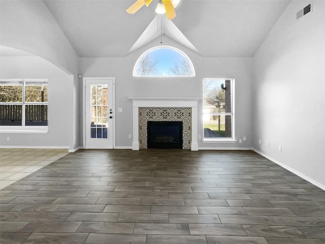 unfurnished living room with ceiling fan, a fireplace, vaulted ceiling, and a wealth of natural light