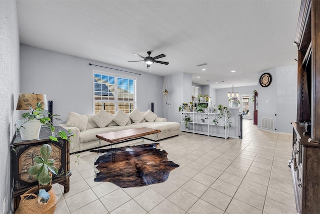 tiled living room with ceiling fan with notable chandelier and a textured ceiling