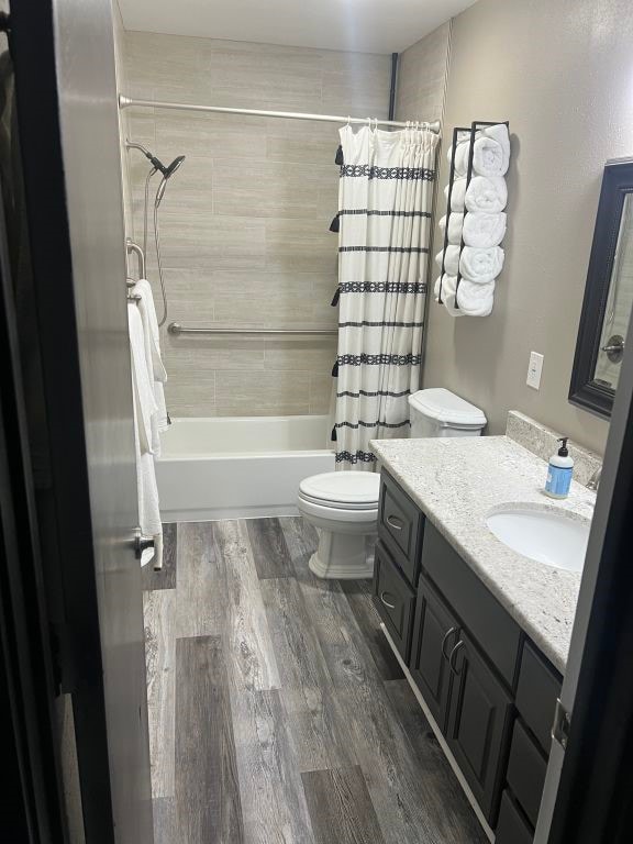 full bathroom featuring vanity, toilet, hardwood / wood-style floors, and shower / tub combo with curtain