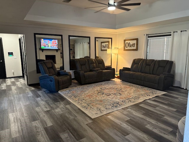 living room with ceiling fan, dark hardwood / wood-style flooring, and a raised ceiling