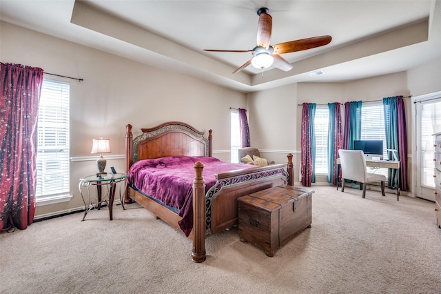 bedroom featuring ceiling fan, light carpet, and a raised ceiling