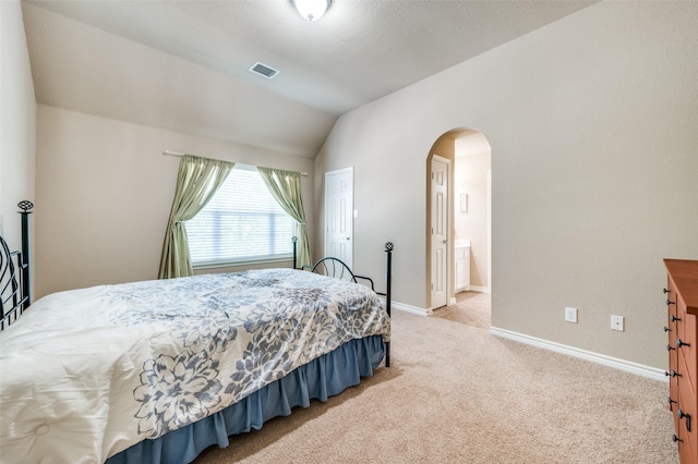 carpeted bedroom featuring connected bathroom and lofted ceiling