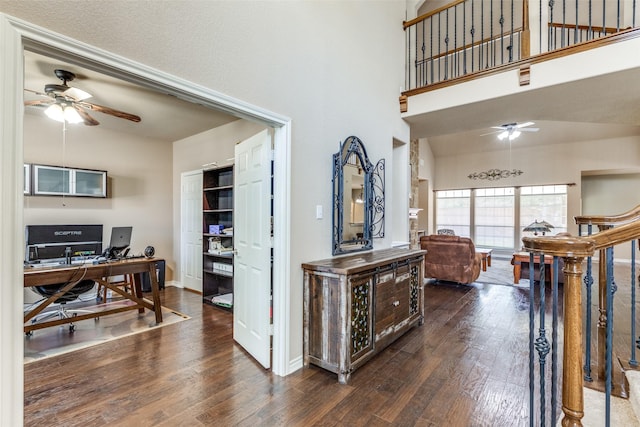 interior space featuring ceiling fan, a high ceiling, and dark wood-type flooring