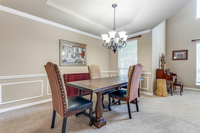 dining room with a notable chandelier, a raised ceiling, light colored carpet, and ornamental molding