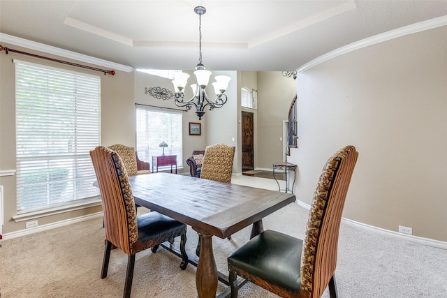 carpeted dining space featuring a chandelier, a raised ceiling, and a healthy amount of sunlight