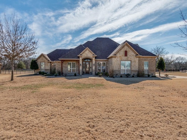 french country style house with french doors, roof with shingles, and fence