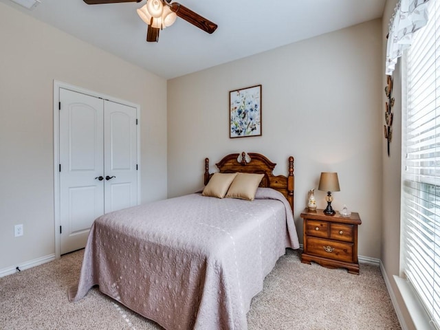 bedroom with a closet, ceiling fan, and light colored carpet