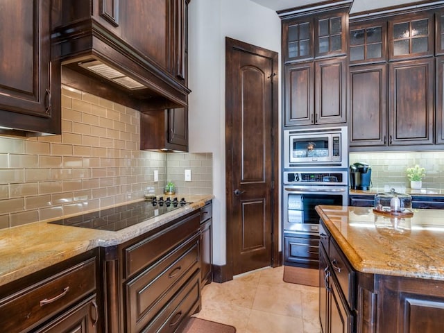 kitchen with dark brown cabinets, backsplash, stainless steel appliances, and custom range hood