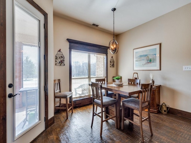 dining space with dark hardwood / wood-style floors and a notable chandelier