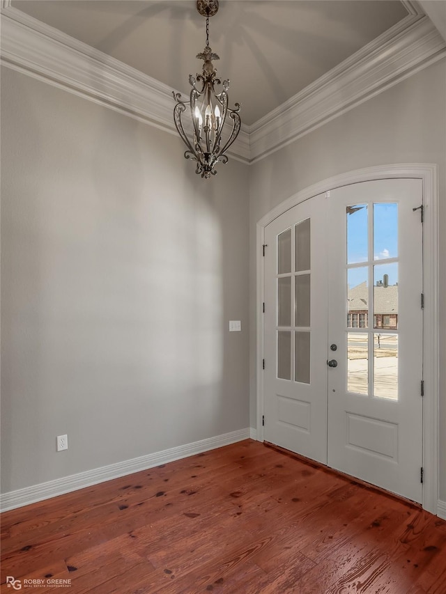 foyer with french doors, crown molding, a chandelier, and hardwood / wood-style floors