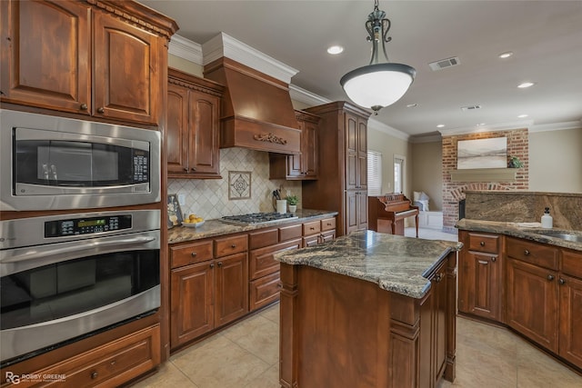 kitchen featuring stainless steel appliances, crown molding, dark stone countertops, and decorative light fixtures