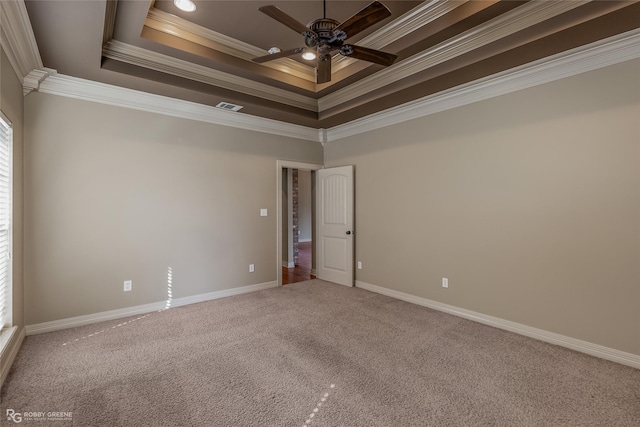 empty room featuring a raised ceiling, ornamental molding, carpet flooring, and ceiling fan