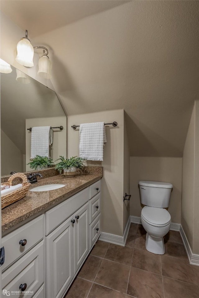 bathroom with vanity, tile patterned flooring, vaulted ceiling, and toilet