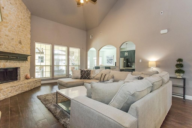 living room with ceiling fan, a high ceiling, and a fireplace