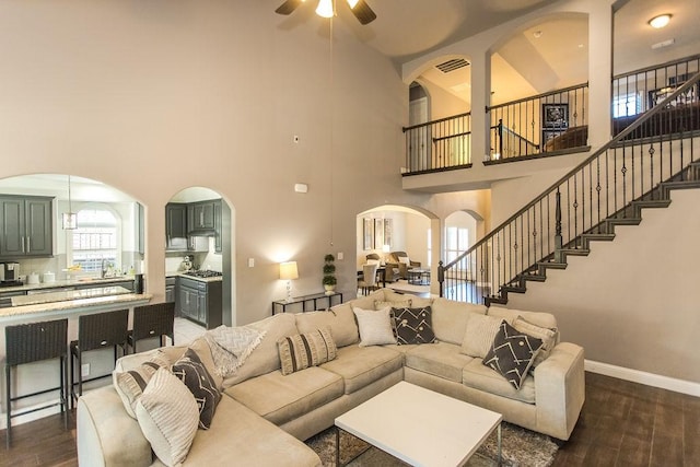 living room with dark wood-type flooring, a high ceiling, sink, and ceiling fan