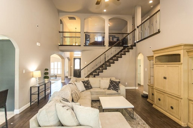 living room featuring ceiling fan, a high ceiling, and dark hardwood / wood-style flooring