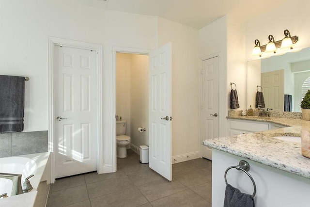 bathroom featuring a washtub, toilet, vanity, and tile patterned flooring