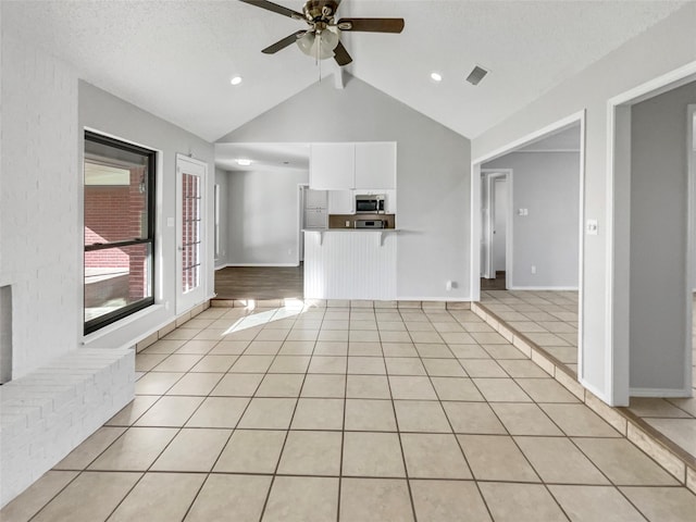 unfurnished living room featuring light tile patterned flooring, vaulted ceiling with beams, a textured ceiling, and ceiling fan