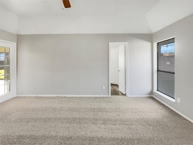 empty room with vaulted ceiling, ceiling fan, and carpet flooring