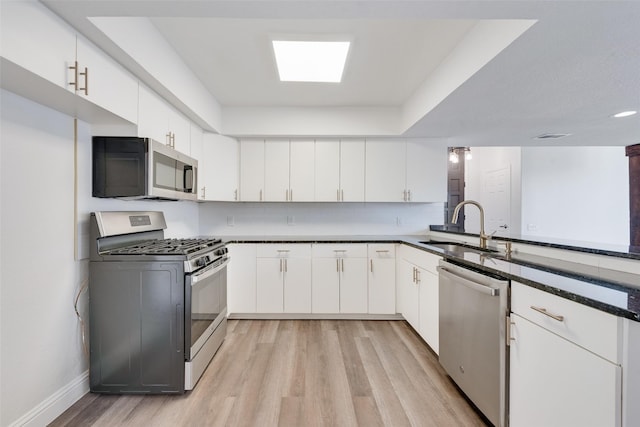 kitchen with light hardwood / wood-style flooring, a raised ceiling, sink, white cabinetry, and stainless steel appliances