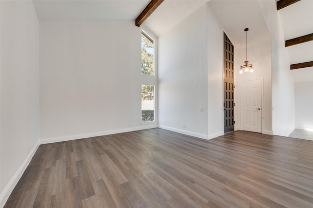 empty room featuring wood-type flooring, beam ceiling, high vaulted ceiling, and a notable chandelier