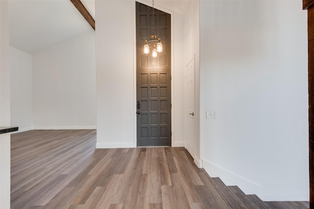 entryway featuring hardwood / wood-style floors, beam ceiling, and an inviting chandelier