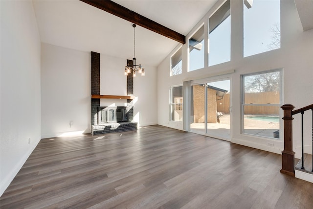 unfurnished living room with a high ceiling, hardwood / wood-style flooring, a fireplace, and a healthy amount of sunlight