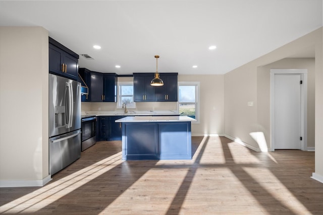 kitchen featuring stainless steel refrigerator with ice dispenser, decorative light fixtures, sink, stove, and light hardwood / wood-style floors