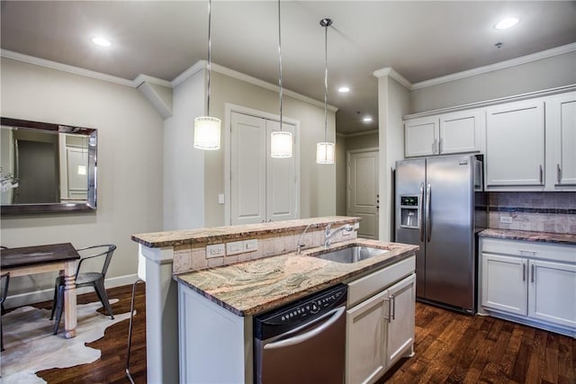 kitchen with decorative light fixtures, sink, white cabinets, an island with sink, and stainless steel appliances