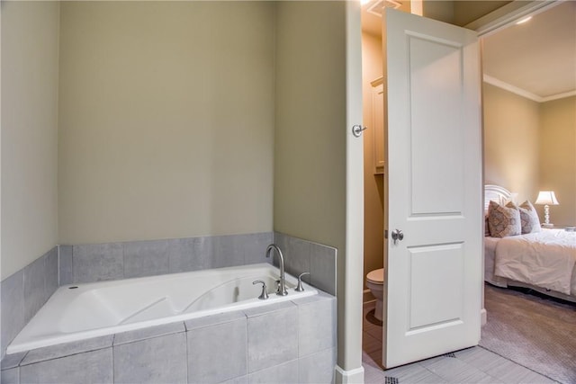 bathroom featuring tile patterned floors, tiled tub, toilet, and ornamental molding