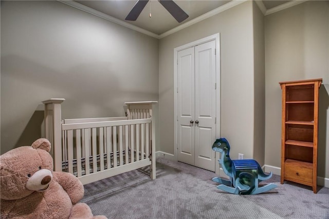 carpeted bedroom featuring ceiling fan, a closet, crown molding, and a crib