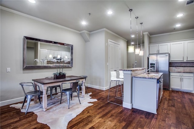 kitchen featuring decorative light fixtures, white cabinetry, a kitchen bar, and a kitchen island with sink