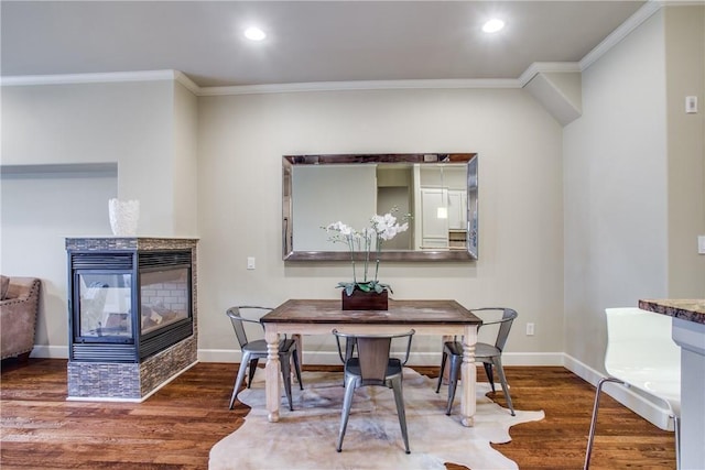 dining area featuring a multi sided fireplace, ornamental molding, and wood-type flooring