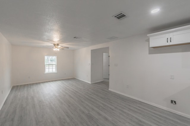 spare room featuring light wood-type flooring, a textured ceiling, and ceiling fan