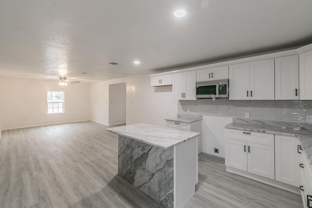 kitchen featuring light stone counters, white cabinets, and a kitchen island