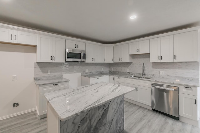 kitchen featuring sink, white cabinets, light wood-type flooring, stainless steel appliances, and light stone counters