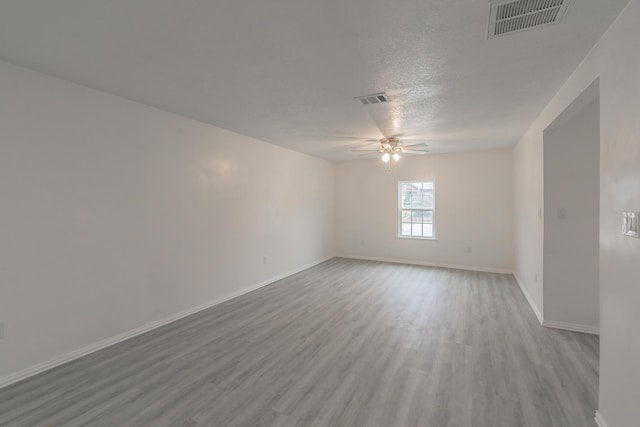 empty room with light wood-type flooring, ceiling fan, and a textured ceiling