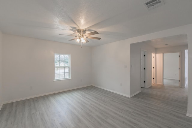 empty room featuring ceiling fan, light hardwood / wood-style floors, and a textured ceiling