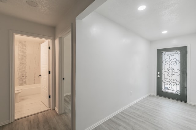 foyer with a textured ceiling and light hardwood / wood-style flooring