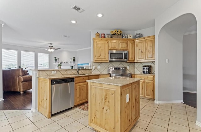 kitchen with a kitchen island, kitchen peninsula, backsplash, stainless steel appliances, and light brown cabinets