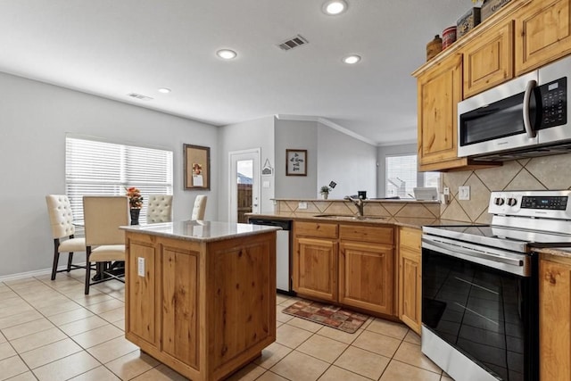 kitchen featuring sink, a kitchen island, backsplash, stainless steel appliances, and light tile patterned flooring