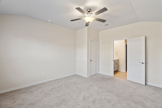 unfurnished bedroom with ceiling fan, light colored carpet, ensuite bath, and vaulted ceiling