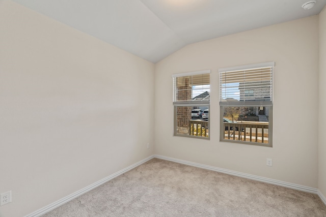 carpeted spare room with vaulted ceiling