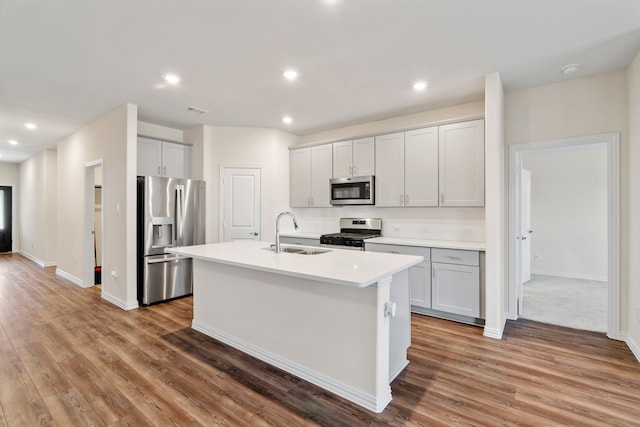 kitchen with light hardwood / wood-style floors, sink, a center island with sink, and stainless steel appliances