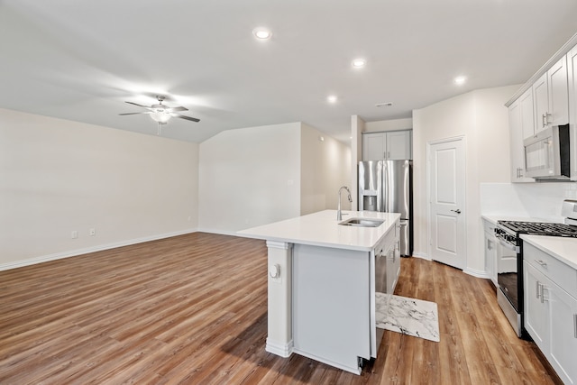 kitchen featuring light hardwood / wood-style floors, appliances with stainless steel finishes, a kitchen island with sink, sink, and white cabinets