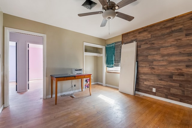 interior space featuring wood walls, light wood-type flooring, and ceiling fan