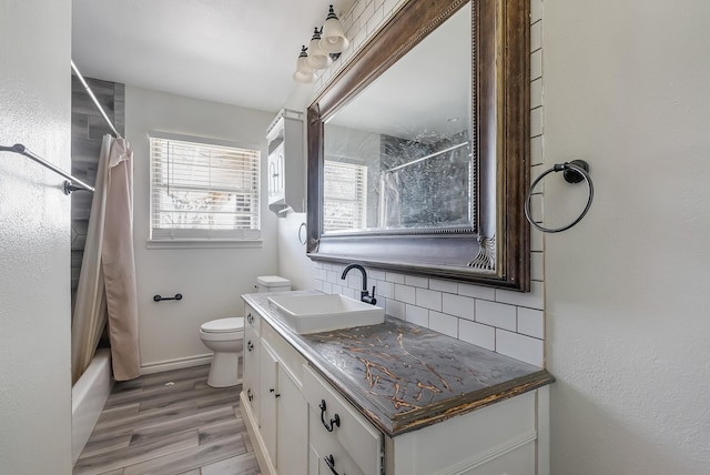 full bathroom with hardwood / wood-style floors, vanity, decorative backsplash, toilet, and shower / bath combo with shower curtain