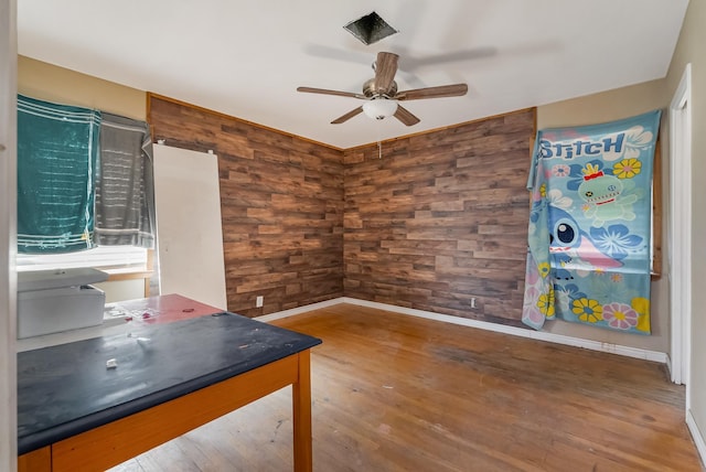 unfurnished office featuring wood-type flooring, wooden walls, and ceiling fan