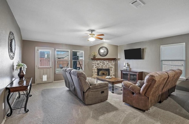 living room featuring ceiling fan, light colored carpet, a textured ceiling, and a fireplace