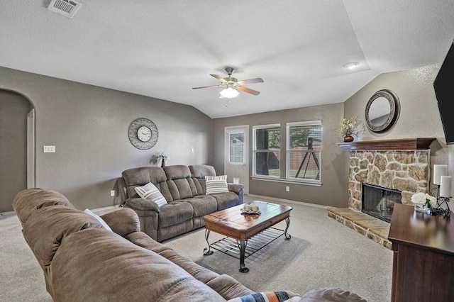 living room with vaulted ceiling, ceiling fan, light colored carpet, a fireplace, and a textured ceiling